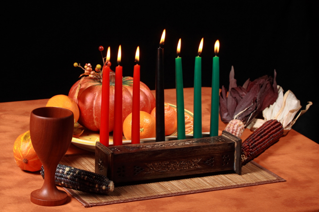 Table set with traditional candle holder, a cup, corn, and gourds.